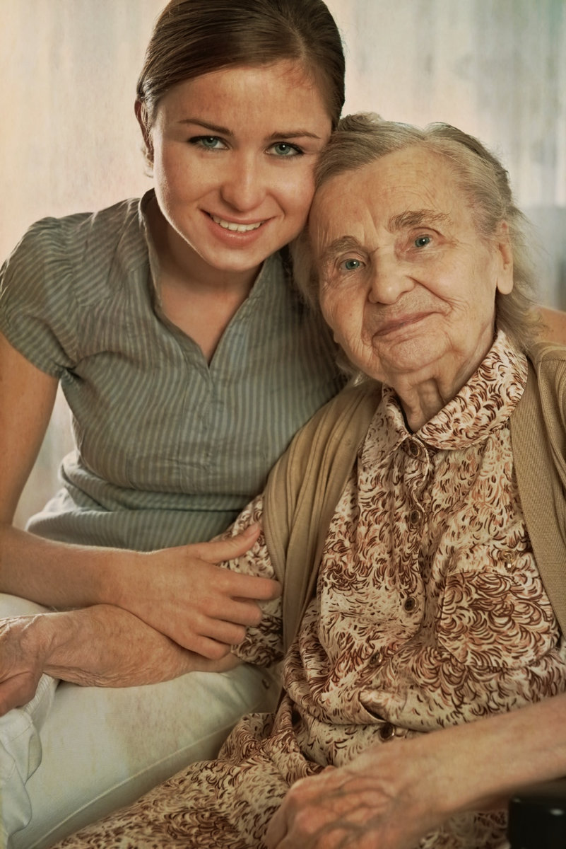 a female caregiver hugging her elderly female client